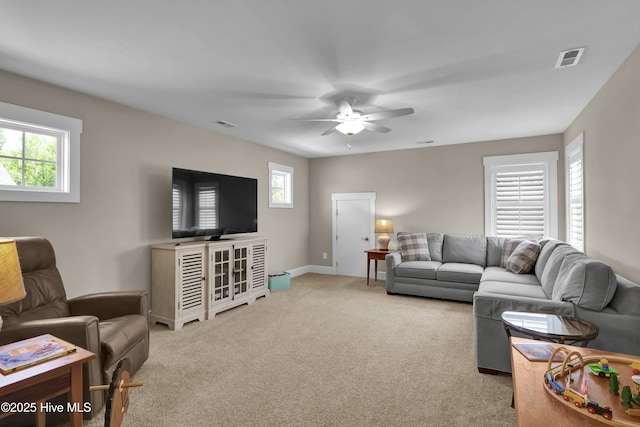 living area with visible vents, a ceiling fan, baseboards, and light carpet