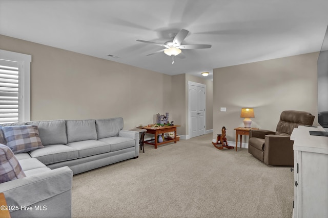 living area featuring a ceiling fan, baseboards, visible vents, and light carpet