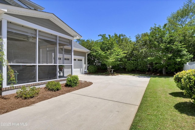 view of home's exterior featuring a lawn, an attached garage, driveway, and a sunroom