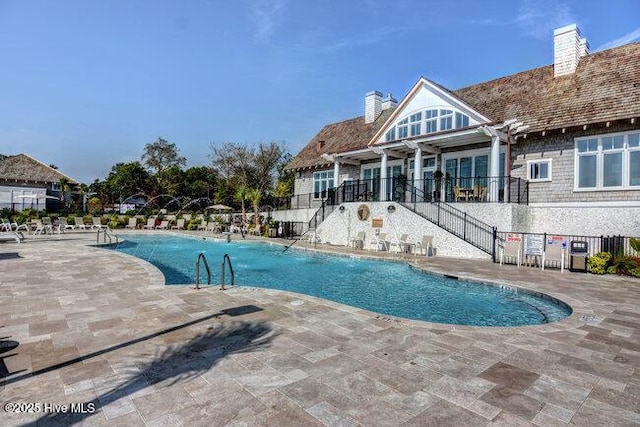 community pool with a pergola, fence, and a patio area