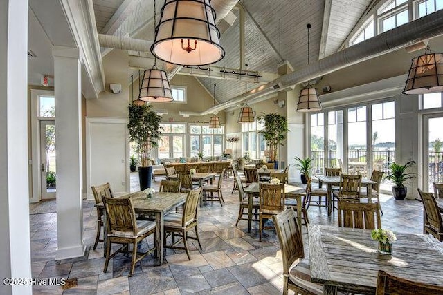 dining room featuring beam ceiling, high vaulted ceiling, decorative columns, wood ceiling, and stone tile flooring