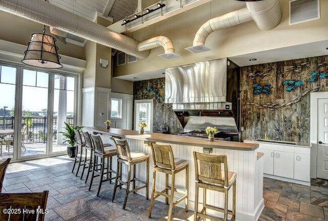 kitchen with white cabinetry, a high ceiling, visible vents, and stone tile flooring