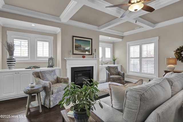 living area with dark wood-type flooring, ornamental molding, coffered ceiling, and ceiling fan