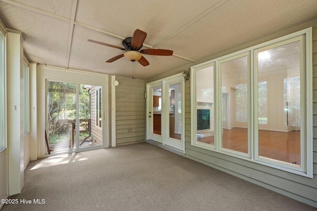 unfurnished sunroom with a ceiling fan and carpet floors
