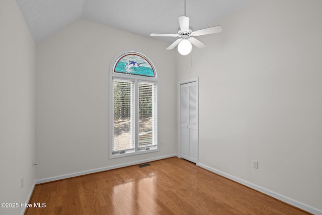 empty room with baseboards, wood finished floors, a ceiling fan, and lofted ceiling