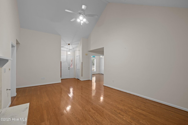 unfurnished living room featuring high vaulted ceiling, baseboards, a ceiling fan, and wood finished floors