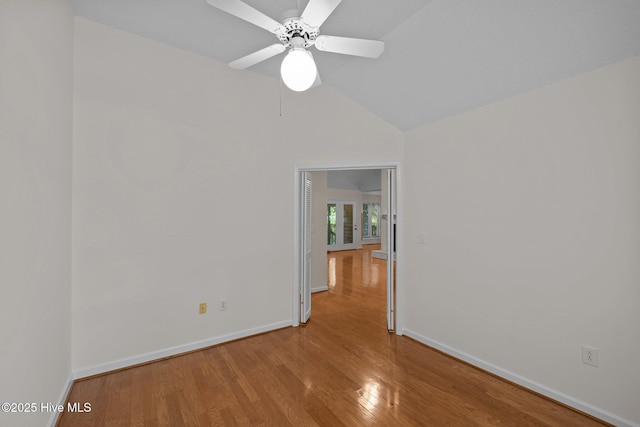 empty room with wood finished floors, baseboards, a ceiling fan, and lofted ceiling