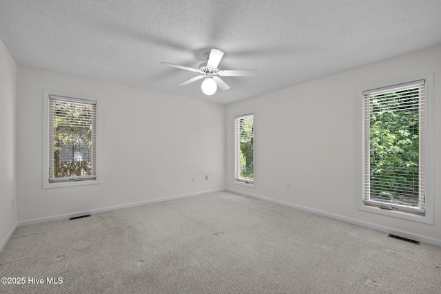 unfurnished room featuring visible vents, baseboards, and plenty of natural light