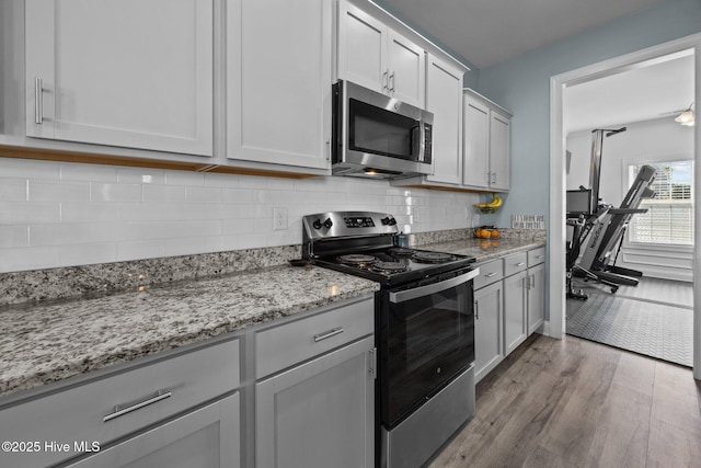 506 White Shoal Way, Sneads Ferry, NC 28460 - kitchen featuring light stone counters, backsplash, wood finished floors, and stainless steel appliances