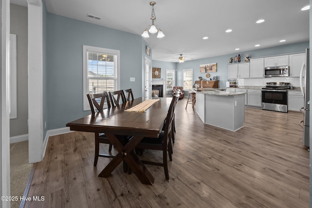506 White Shoal Way, Sneads Ferry, NC 28460 - dining space featuring a ceiling fan, visible vents, wood finished floors, a glass covered fireplace, and recessed lighting