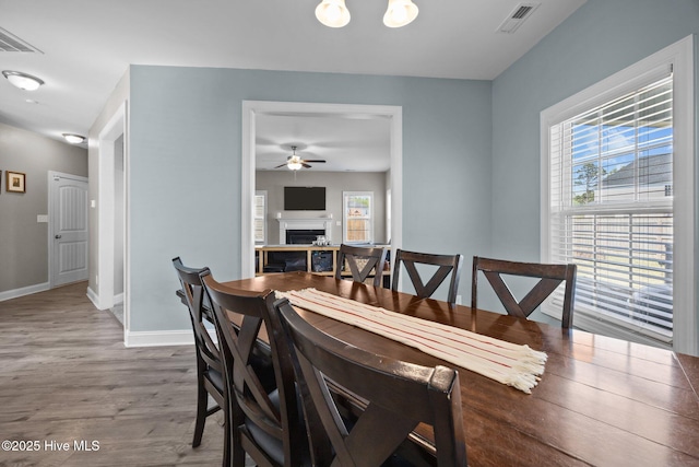 506 White Shoal Way, Sneads Ferry, NC 28460 - dining area with a ceiling fan, visible vents, a fireplace, wood finished floors, and baseboards