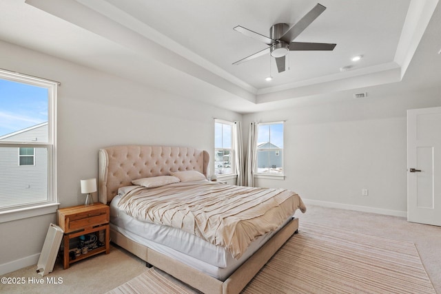 bedroom with visible vents, baseboards, a raised ceiling, and light carpet