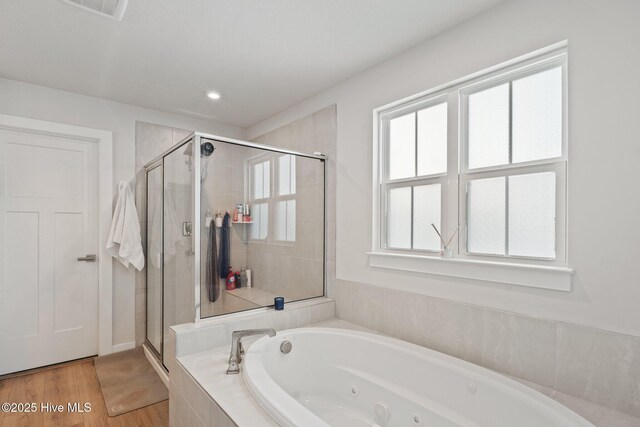 full bath with a whirlpool tub, a shower stall, wood finished floors, and visible vents
