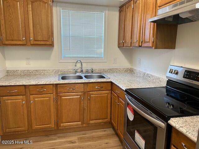 409 E Broad St, Elizabeth City, NC 27909 - kitchen featuring brown cabinets, under cabinet range hood, a sink, and electric stove
