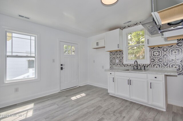 504 Belmont Ave SW, Wilson, NC 27893 - kitchen with tasteful backsplash, light wood finished floors, a sink, and white cabinetry