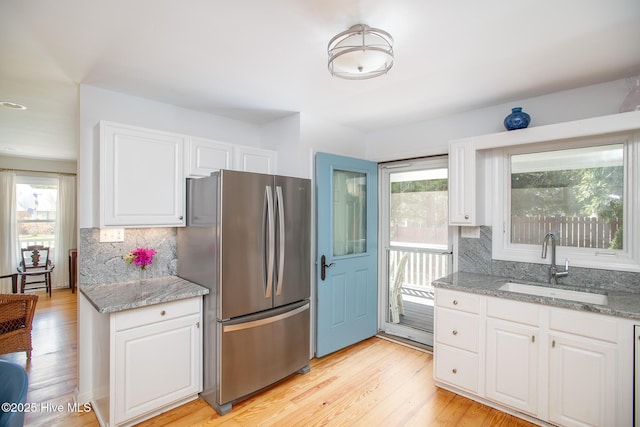 101 Beaufort Walk, Beaufort, NC 28516 - kitchen with light stone countertops, a sink, freestanding refrigerator, and white cabinetry