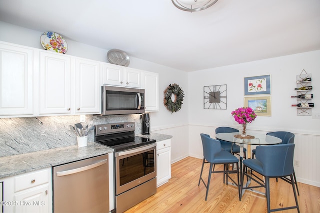 101 Beaufort Walk, Beaufort, NC 28516 - kitchen with stainless steel appliances, light wood-style floors, white cabinetry, and light stone counters