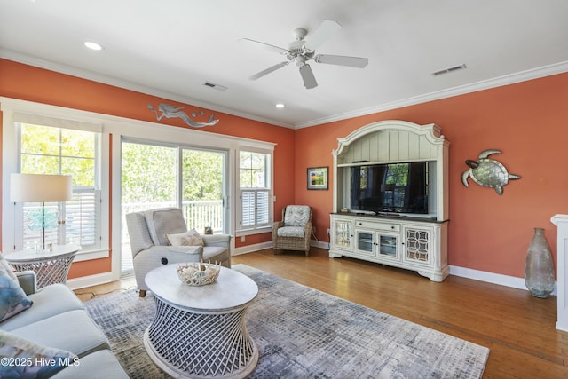 living area with ceiling fan, crown molding, visible vents, baseboards, and wood finished floors