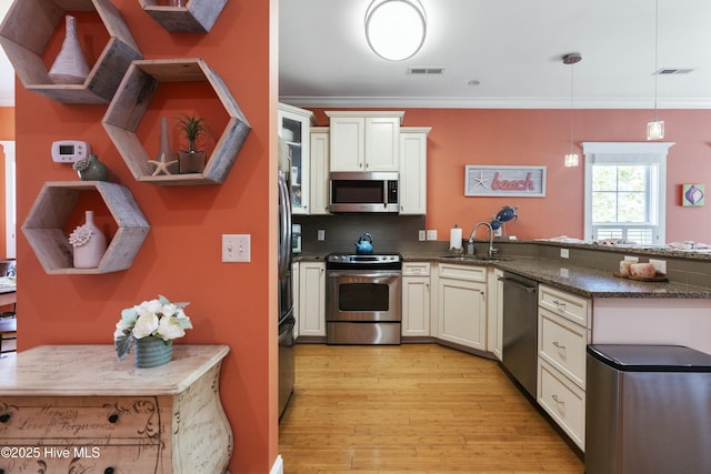 kitchen with ornamental molding, a sink, stainless steel appliances, and visible vents