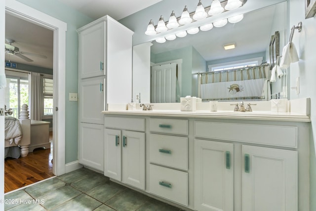 full bath featuring connected bathroom, tile patterned flooring, double vanity, ceiling fan, and a sink
