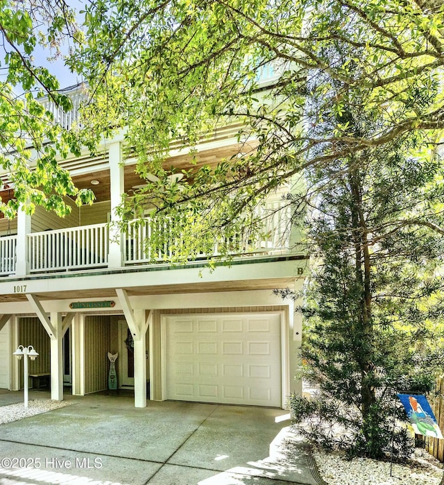 view of front facade featuring concrete driveway, a balcony, and an attached garage