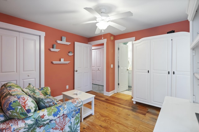 interior space featuring connected bathroom, a closet, baseboards, light wood-type flooring, and a ceiling fan