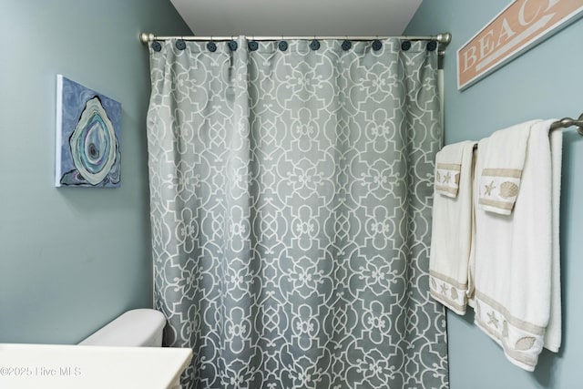 bathroom featuring toilet and a shower with curtain