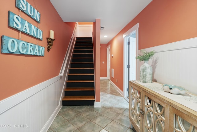stairs featuring a wainscoted wall and tile patterned floors