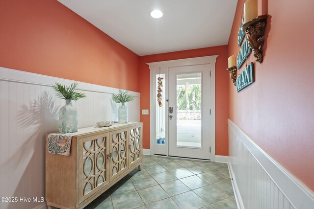doorway to outside featuring tile patterned flooring and wainscoting