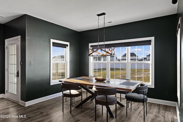 dining space featuring baseboards, a textured ceiling, and wood finished floors
