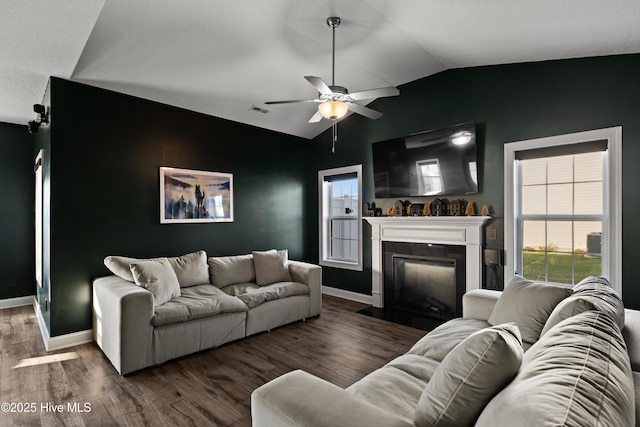 living room featuring visible vents, ceiling fan, vaulted ceiling, wood finished floors, and a fireplace with flush hearth