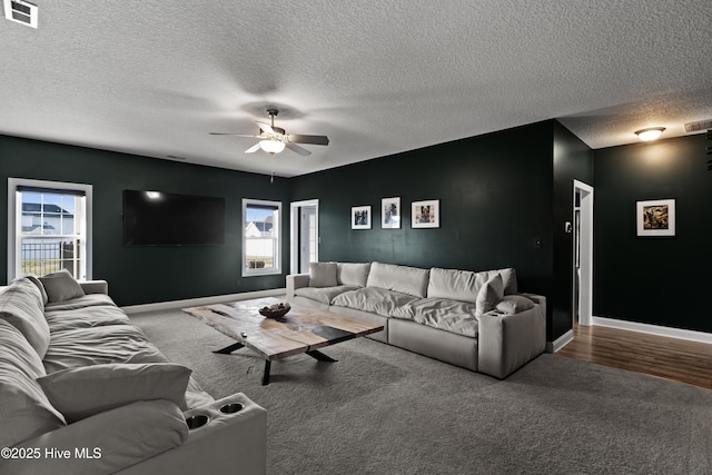 living room with ceiling fan, a textured ceiling, visible vents, carpet flooring, and baseboards