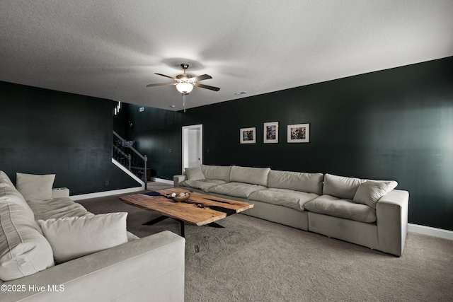 living area featuring stairs, carpet flooring, a textured ceiling, and ceiling fan