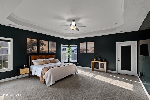 carpeted bedroom with visible vents, baseboards, ornamental molding, and a raised ceiling