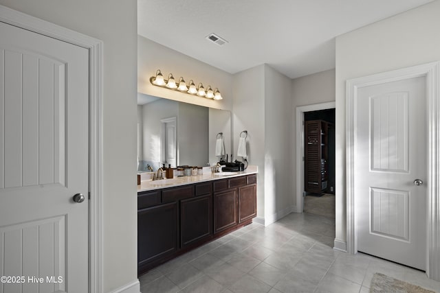 full bath featuring visible vents, a sink, tile patterned floors, double vanity, and baseboards