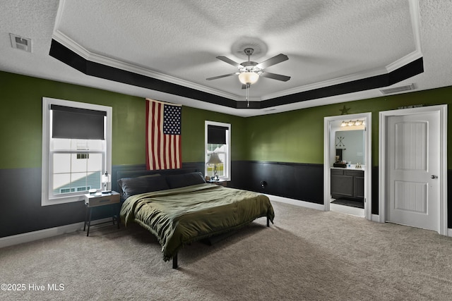 bedroom with visible vents, carpet, a raised ceiling, and wainscoting