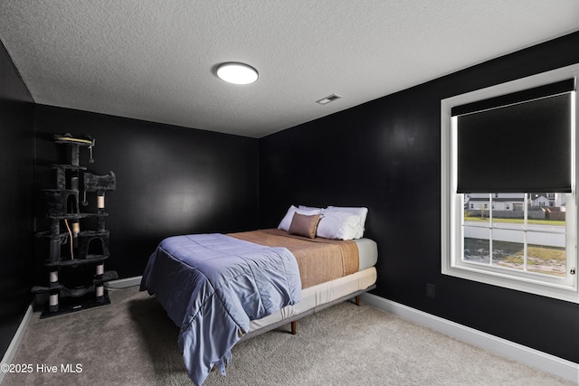 carpeted bedroom featuring visible vents, baseboards, and a textured ceiling