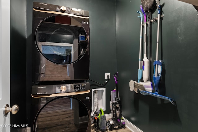 laundry room with baseboards, stacked washer / drying machine, and laundry area
