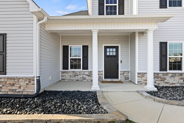 doorway to property featuring stone siding and covered porch