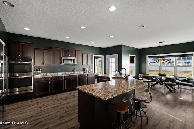 kitchen featuring stainless steel appliances, a notable chandelier, dark wood-style flooring, and a sink
