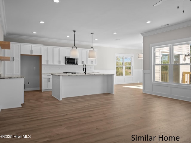 295 E Ivybridge Dr, Hubert, NC 28539 - kitchen featuring stainless steel microwave, white cabinets, ornamental molding, recessed lighting, and a center island with sink