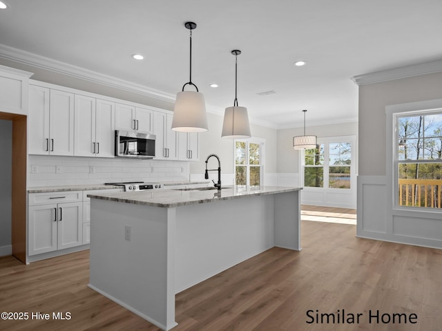 295 E Ivybridge Dr, Hubert, NC 28539 - kitchen with stainless steel microwave, crown molding, white cabinets, light wood-style flooring, and light stone counters
