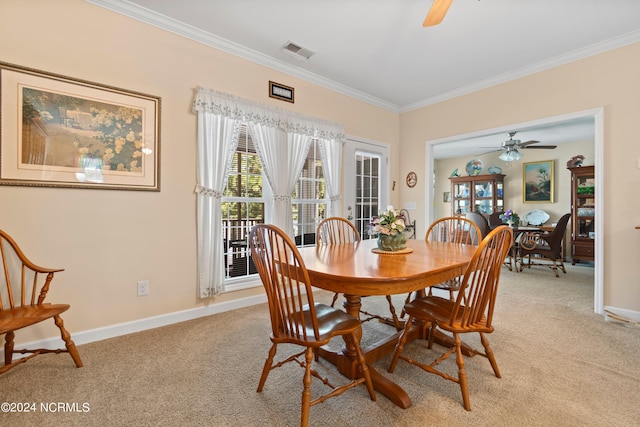 dining room featuring baseboards, light carpet, a ceiling fan, crown molding, and visible vents