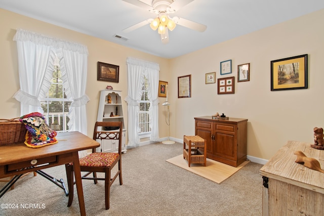 home office with visible vents, baseboards, a ceiling fan, and light carpet