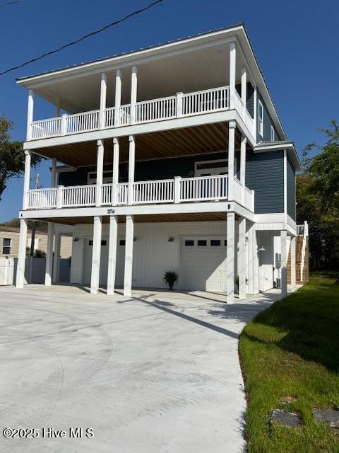 beach home with an attached garage, driveway, and a balcony