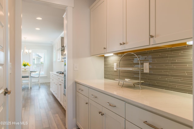 bar with crown molding, wood finished floors, tasteful backsplash, a chandelier, and recessed lighting