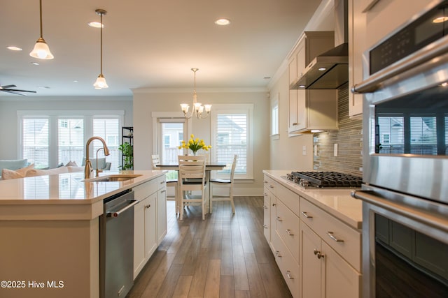 kitchen with a sink, stainless steel appliances, a chandelier, decorative backsplash, and light countertops