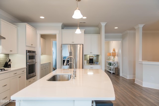 kitchen featuring a sink, stainless steel appliances, backsplash, recessed lighting, and a kitchen island with sink