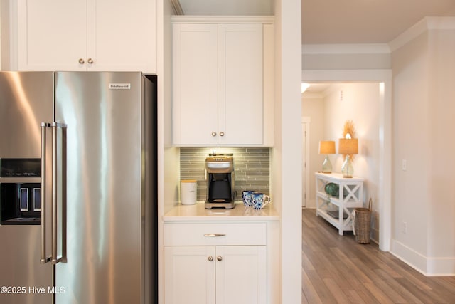 kitchen featuring high quality fridge, baseboards, wood finished floors, tasteful backsplash, and white cabinetry