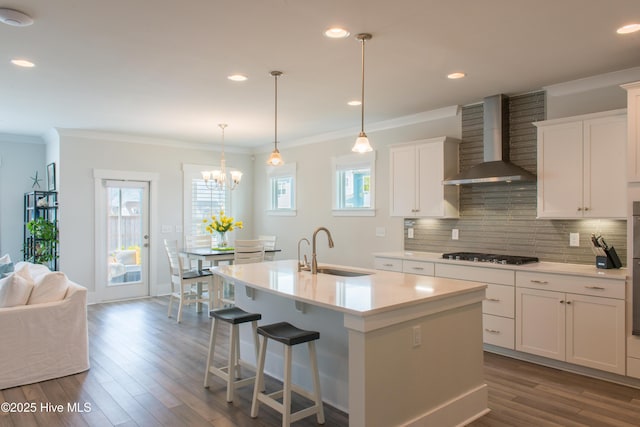 kitchen featuring wall chimney exhaust hood, gas stovetop, a sink, backsplash, and dark wood-type flooring